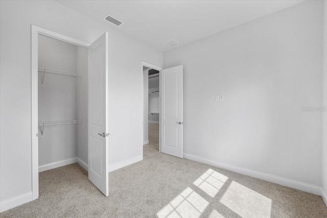 unfurnished bedroom with light colored carpet and a closet