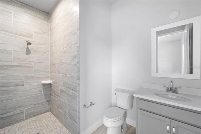 bathroom with tiled shower, toilet, and vanity