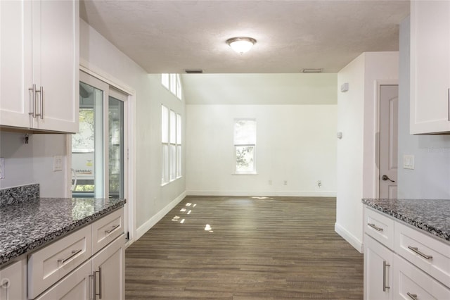 kitchen featuring white cabinetry, dark stone counters, and dark hardwood / wood-style flooring