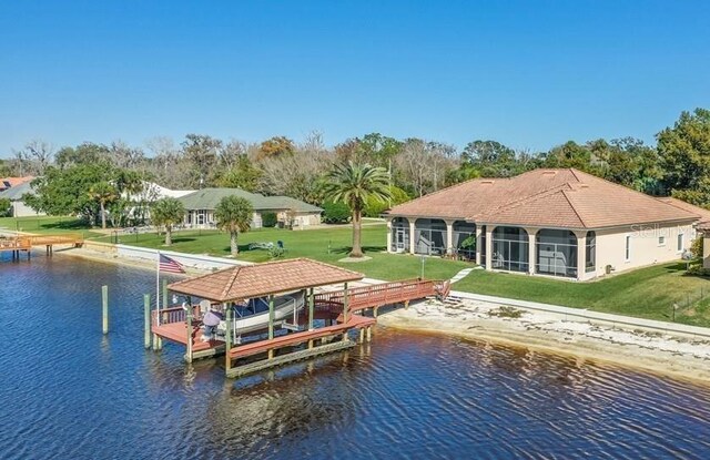 dock area featuring a water view, boat lift, and a yard