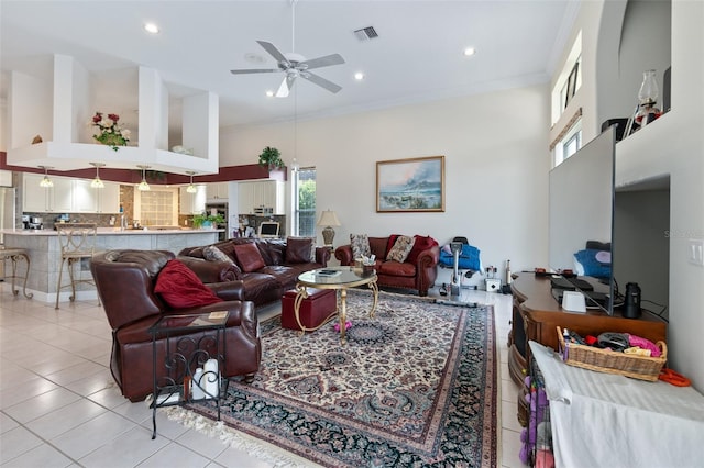 living area featuring visible vents, crown molding, a towering ceiling, and light tile patterned floors