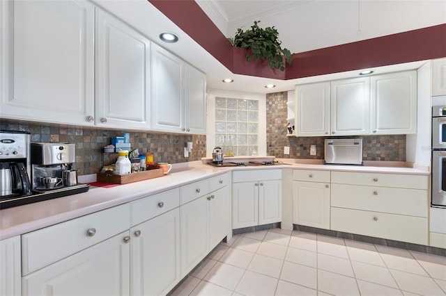 kitchen with light countertops, backsplash, ornamental molding, white cabinetry, and black electric cooktop