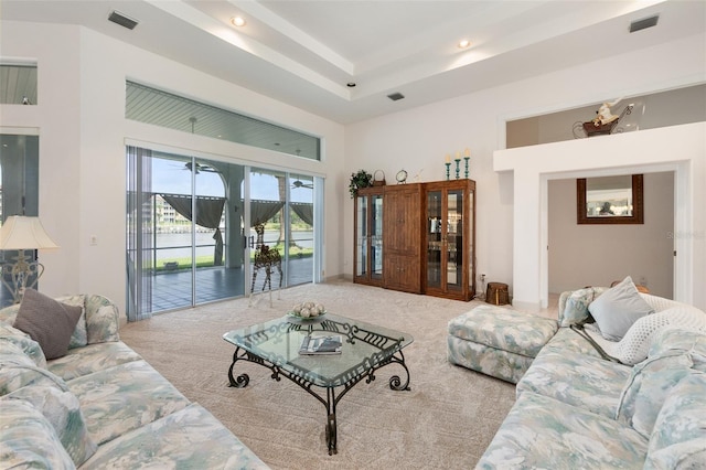 living room with light carpet, a towering ceiling, and visible vents