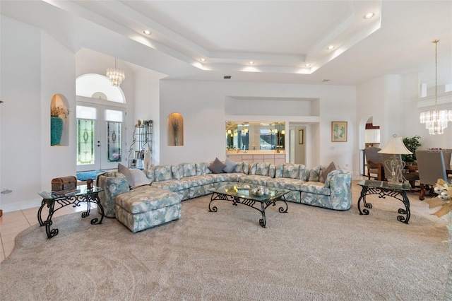 living area featuring arched walkways, french doors, a tray ceiling, a chandelier, and tile patterned floors