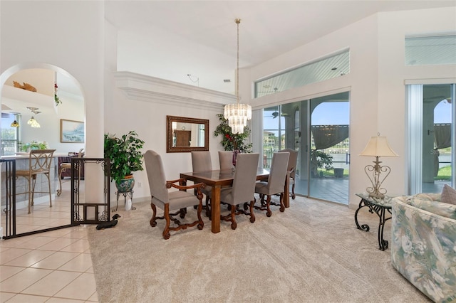 dining room featuring a towering ceiling, light tile patterned floors, plenty of natural light, and an inviting chandelier