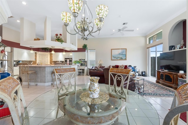 dining area featuring a towering ceiling, ceiling fan with notable chandelier, ornamental molding, and light tile patterned flooring