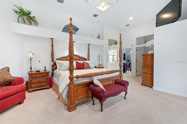 bedroom featuring light carpet, a towering ceiling, visible vents, baseboards, and a spacious closet