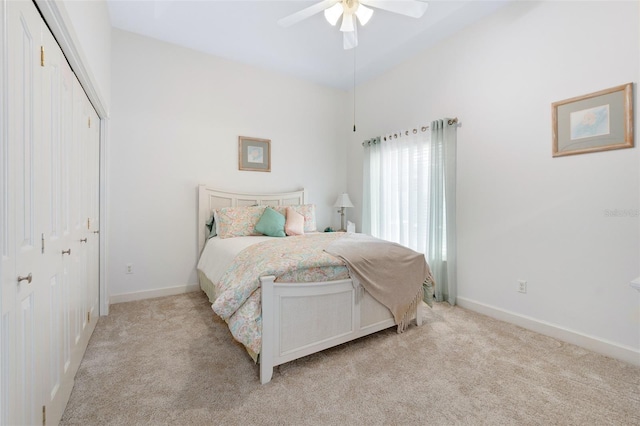 bedroom with a ceiling fan, a closet, light carpet, and baseboards