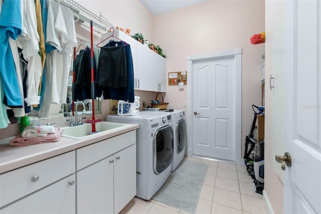 clothes washing area featuring a sink, light tile patterned floors, washing machine and clothes dryer, and cabinet space