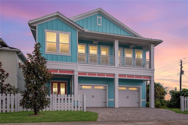 beach home featuring board and batten siding, decorative driveway, fence, and a garage