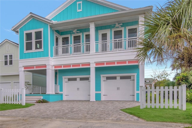 view of front of home featuring a garage, ceiling fan, fence, decorative driveway, and board and batten siding