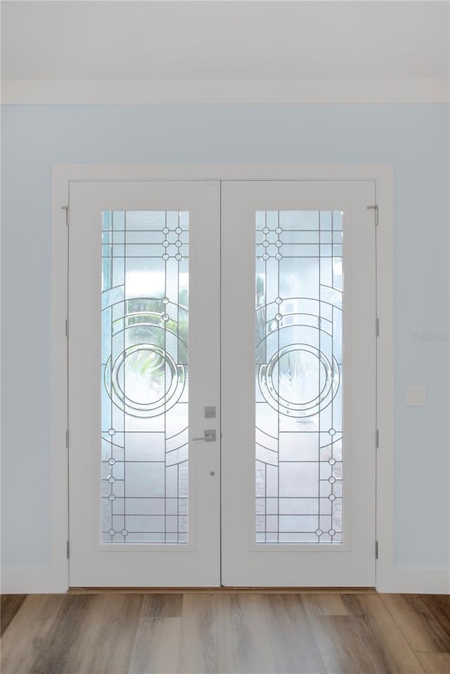 doorway with french doors, baseboards, and wood finished floors