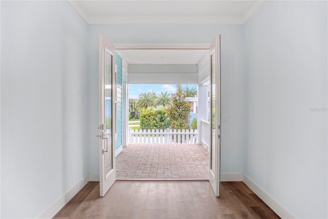 doorway to outside featuring crown molding, wood finished floors, and baseboards