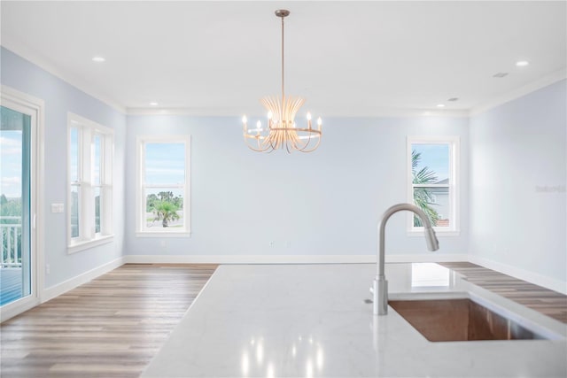 interior space with baseboards, wood finished floors, a sink, and a healthy amount of sunlight