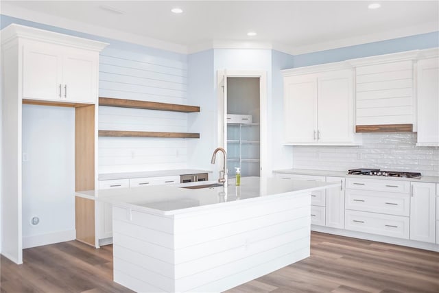 kitchen with stainless steel gas cooktop, light countertops, a kitchen island with sink, white cabinetry, and wood finished floors