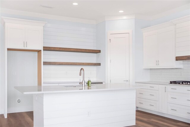 kitchen with light countertops, dark wood finished floors, a center island with sink, and white cabinetry