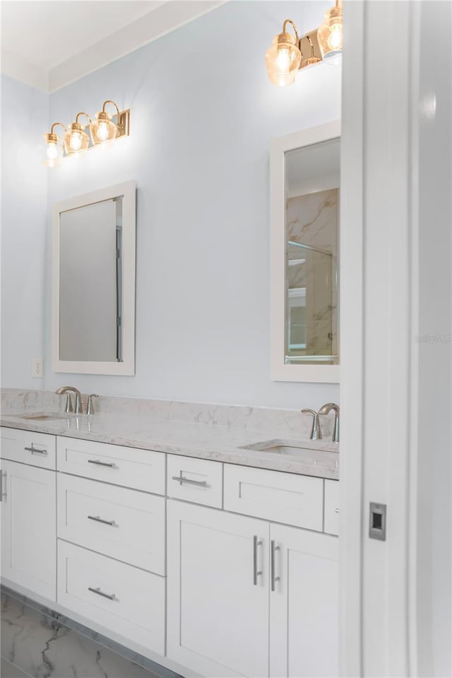 bathroom with marble finish floor, double vanity, and a sink
