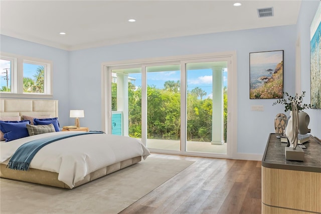bedroom featuring access to exterior, wood finished floors, visible vents, and multiple windows