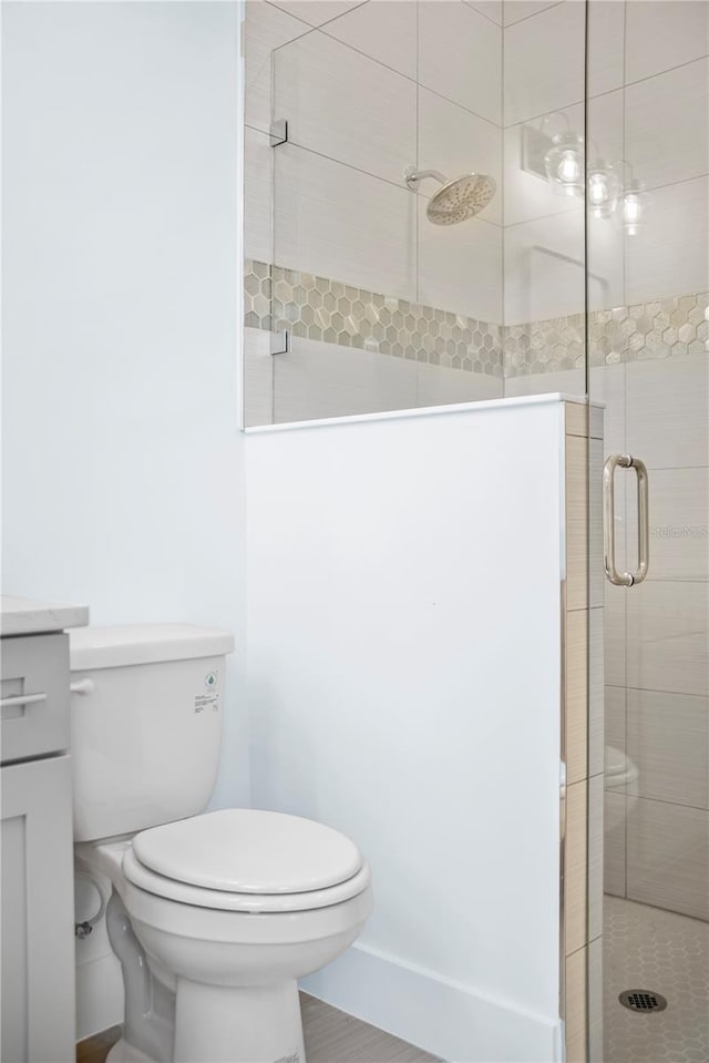bathroom with toilet, a stall shower, and vanity