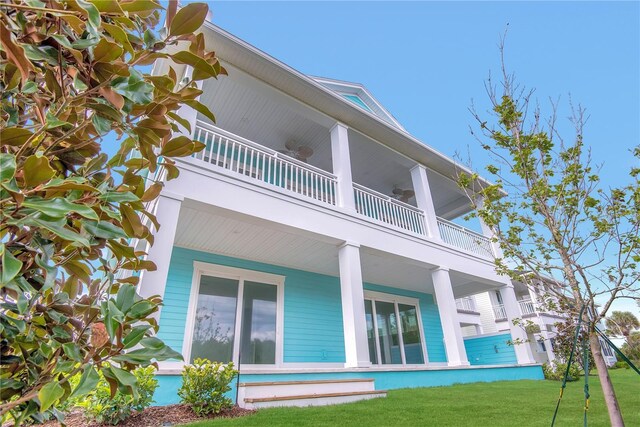 rear view of house with a lawn and a balcony