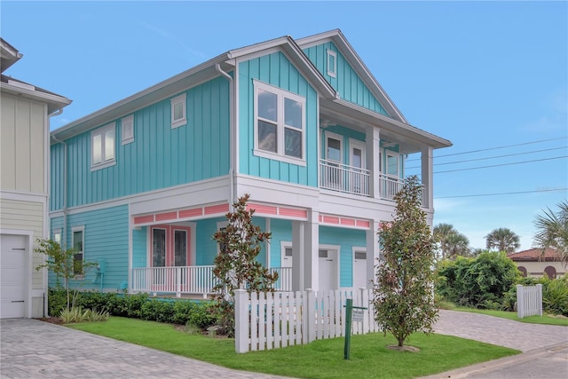 view of front of house featuring a porch, decorative driveway, a front lawn, and board and batten siding