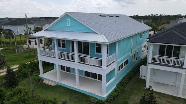 back of property with metal roof, a lawn, a patio area, and roof with shingles