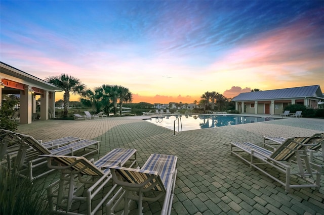 pool at dusk featuring a patio