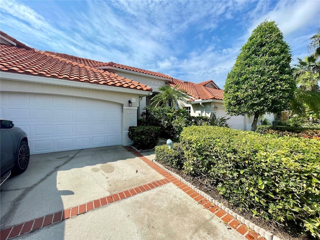 mediterranean / spanish house featuring a tiled roof, concrete driveway, and stucco siding