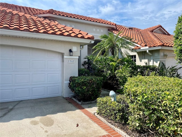 view of front of home featuring a tile roof, stucco siding, driveway, and a garage