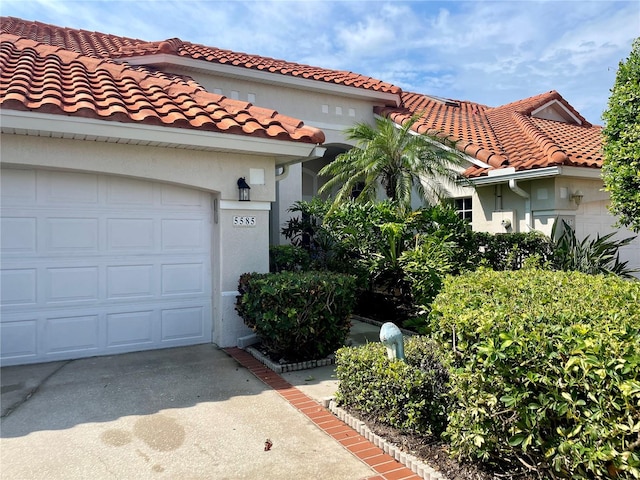 view of front of house featuring stucco siding, an attached garage, driveway, and a tile roof