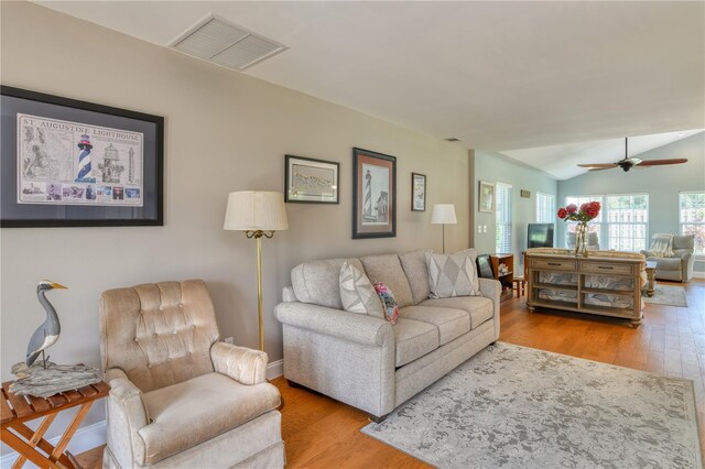 living area with visible vents, a ceiling fan, wood finished floors, baseboards, and lofted ceiling