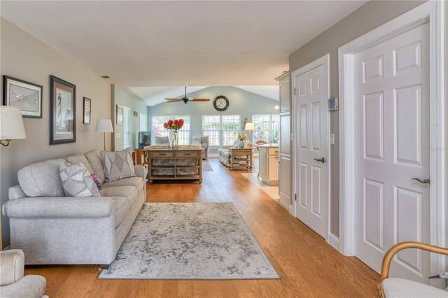 living room featuring light wood-style flooring, a ceiling fan, and vaulted ceiling