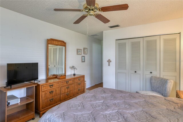 bedroom with ceiling fan, visible vents, a closet, and a textured ceiling