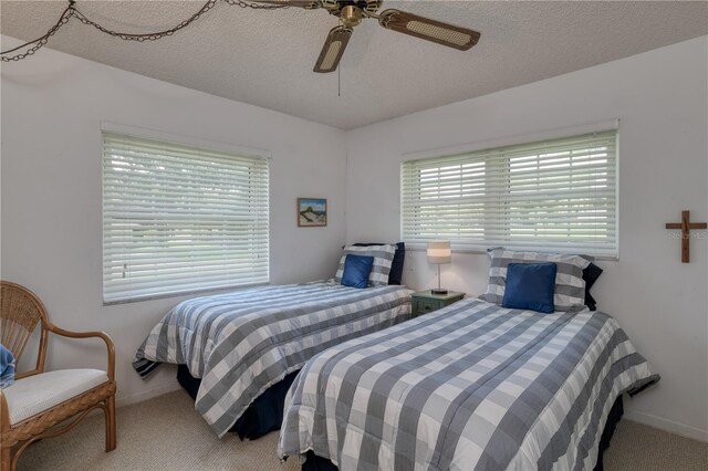 carpeted bedroom with a ceiling fan, baseboards, and a textured ceiling