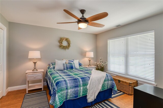 bedroom with ceiling fan, visible vents, baseboards, and wood finished floors