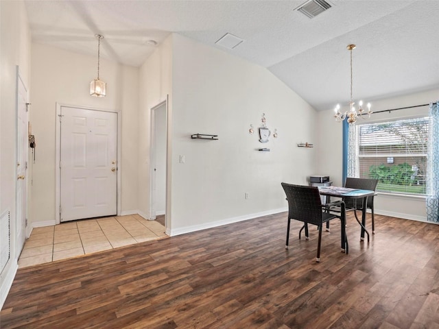 dining space featuring a textured ceiling, lofted ceiling, hardwood / wood-style floors, and a notable chandelier