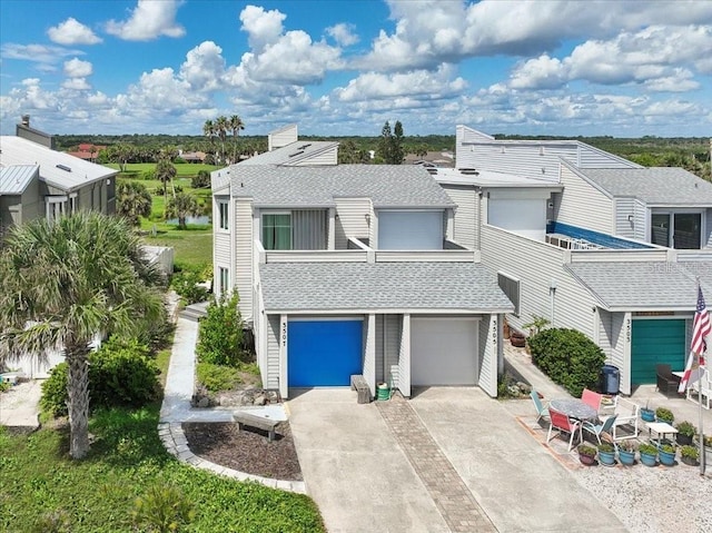 view of front of house featuring a garage, concrete driveway, and roof with shingles