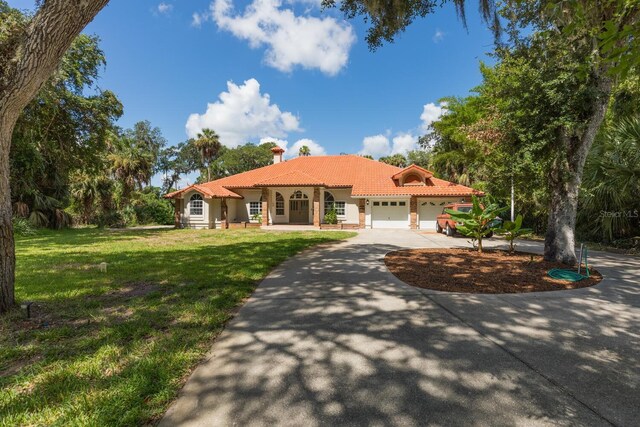 mediterranean / spanish house with a garage and a front yard