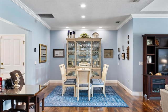 dining space featuring dark hardwood / wood-style flooring, ornamental molding, and a textured ceiling