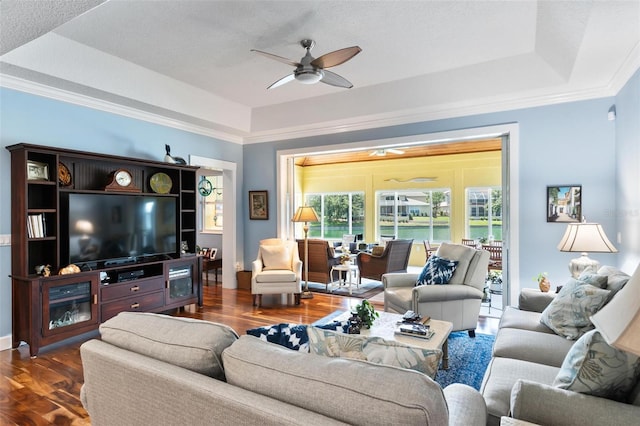 living room featuring ceiling fan, crown molding, hardwood / wood-style flooring, and a tray ceiling