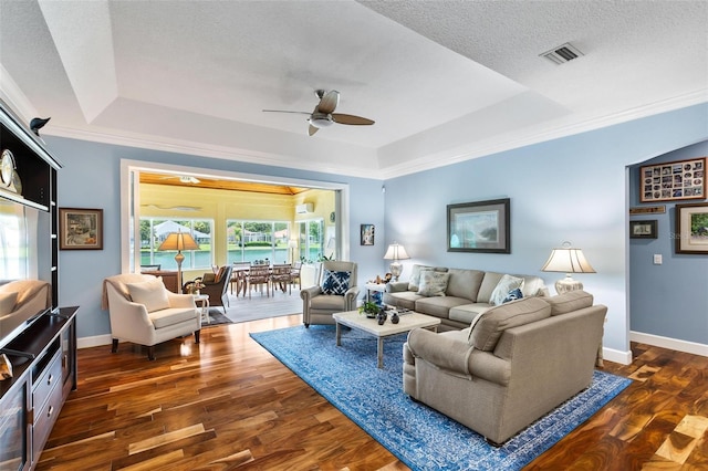 living room featuring ceiling fan, dark wood-type flooring, a textured ceiling, and a tray ceiling