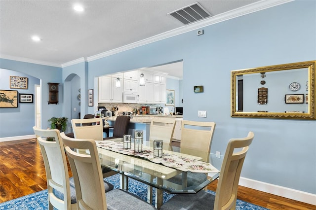 dining room featuring a textured ceiling, ornamental molding, and hardwood / wood-style flooring