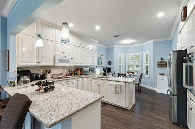 kitchen with dark wood-type flooring, stainless steel appliances, a breakfast bar, kitchen peninsula, and decorative light fixtures