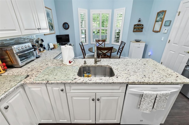 kitchen with white cabinets, dark wood-type flooring, dishwasher, light stone countertops, and sink