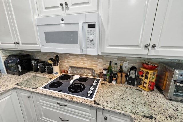 kitchen with decorative backsplash, white cabinets, white appliances, and light stone countertops