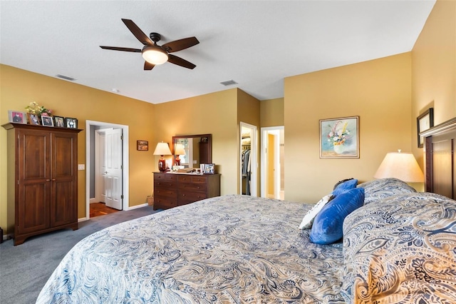 carpeted bedroom featuring a walk in closet, connected bathroom, a closet, and ceiling fan