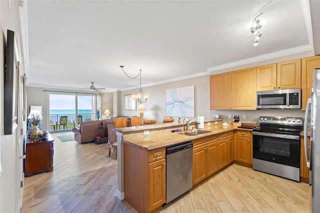 kitchen with track lighting, light stone counters, sink, kitchen peninsula, and stainless steel appliances