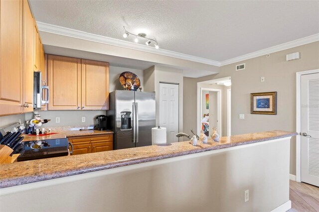 kitchen featuring appliances with stainless steel finishes, light stone countertops, track lighting, a textured ceiling, and kitchen peninsula