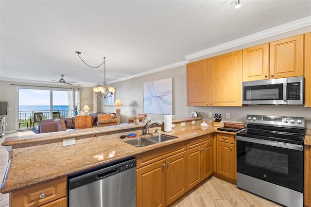 kitchen with a peninsula, a sink, stainless steel appliances, ceiling fan with notable chandelier, and open floor plan