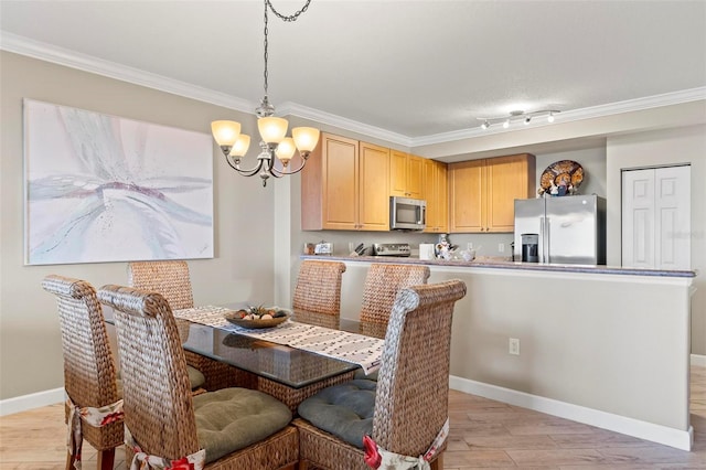 dining space with a notable chandelier, track lighting, light hardwood / wood-style flooring, and ornamental molding